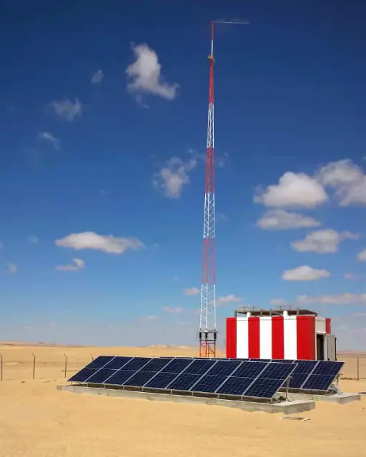 alt="Solar panels and a telecommunications tower in a desert environment for sustainable energy and communication"